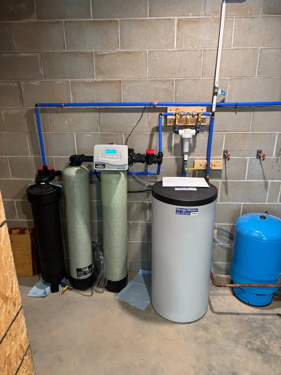 Hellenbrand water softener with sediment and carbon filter tanks installed by Range Water in a block basement