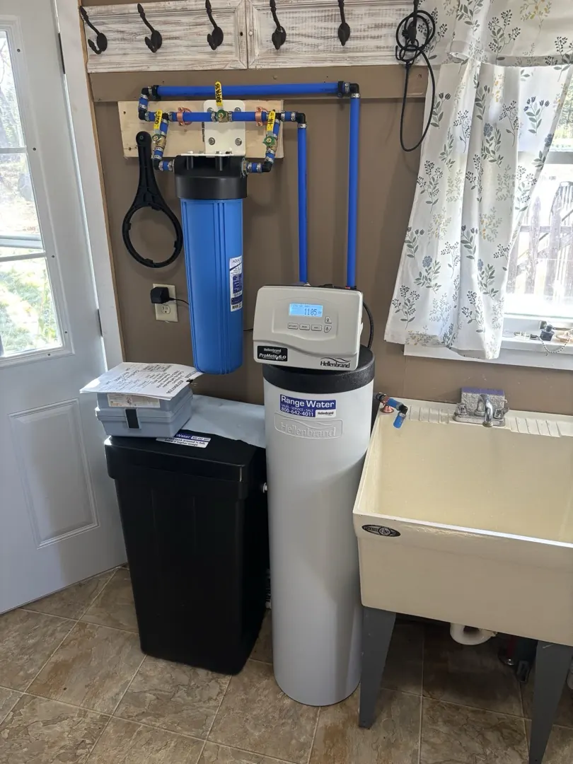 Hellenbrand water softener and whole house sediment filter installed in a laundry room next to a utility sink