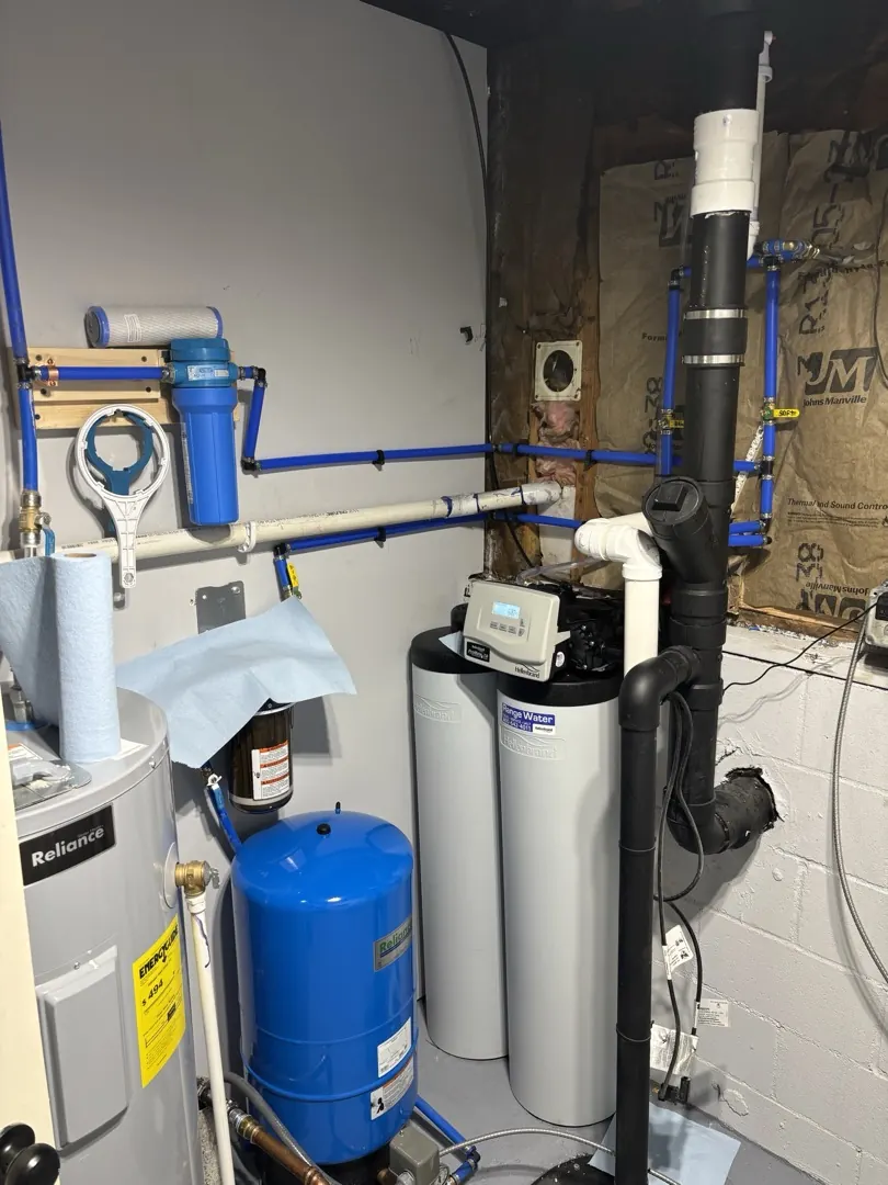 Whole house sediment filter, water softener, and pressure tank installed in a mechanical room