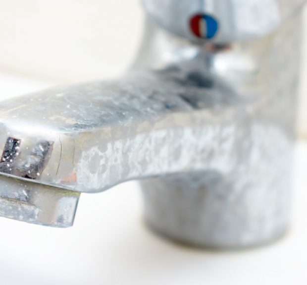 Dirty faucet with limescale, calcified water tap with lime scale on washbowl in bathroom.